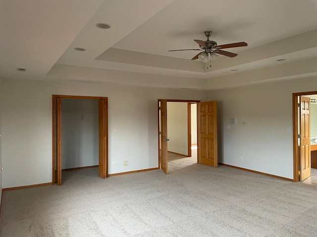 carpeted spare room with ceiling fan and a tray ceiling