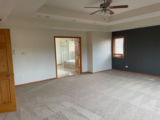 carpeted empty room featuring ceiling fan and a raised ceiling