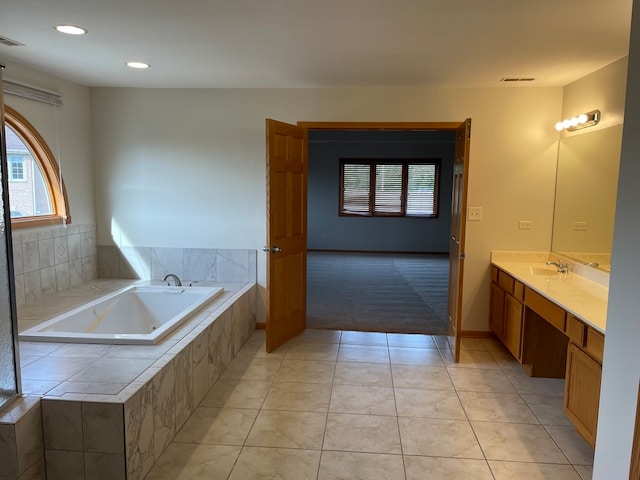 bathroom featuring vanity, tile patterned flooring, and tiled bath