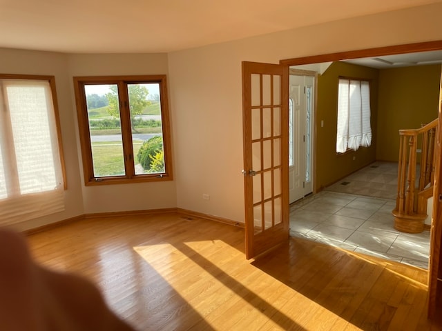 spare room featuring french doors and light hardwood / wood-style floors