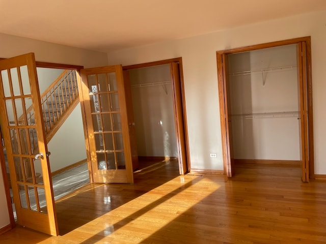 unfurnished bedroom featuring french doors, wood-type flooring, and a closet