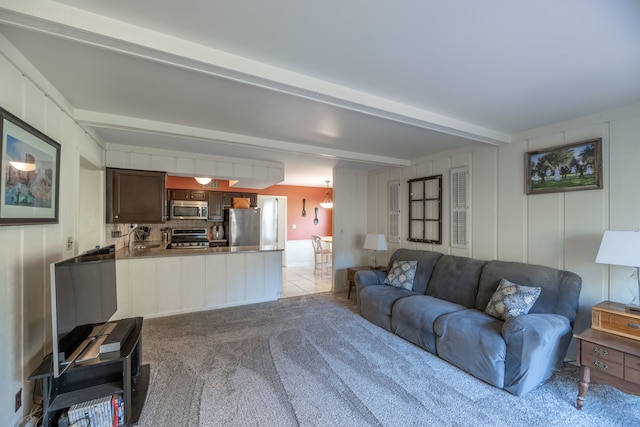 living room with beam ceiling and light colored carpet