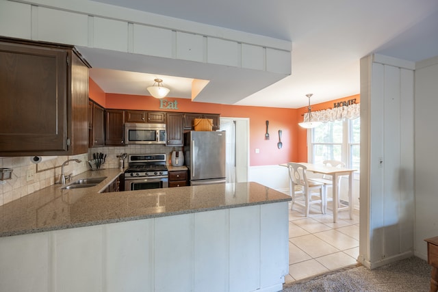 kitchen featuring light stone counters, sink, decorative light fixtures, and appliances with stainless steel finishes