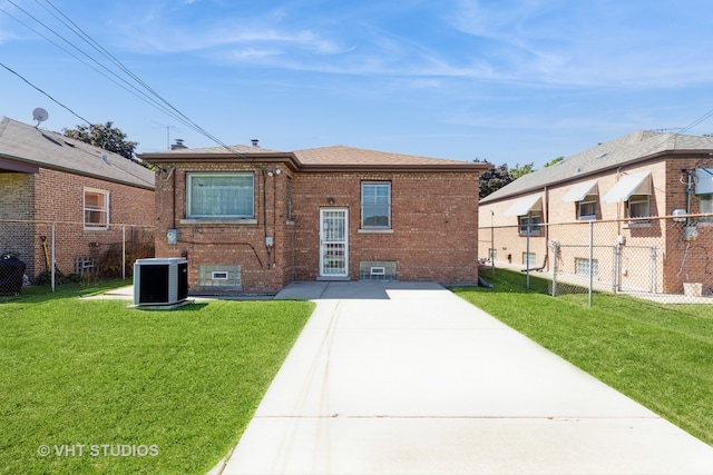 rear view of house with central AC unit and a lawn