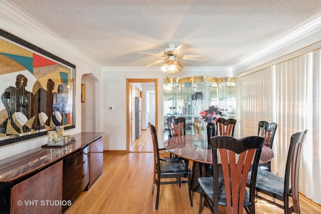 dining room featuring light wood-type flooring, ceiling fan, ornamental molding, and a textured ceiling