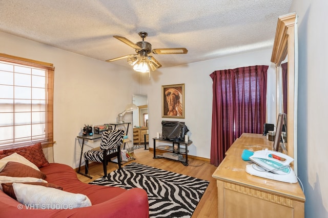 living room featuring ceiling fan, a textured ceiling, and light hardwood / wood-style flooring