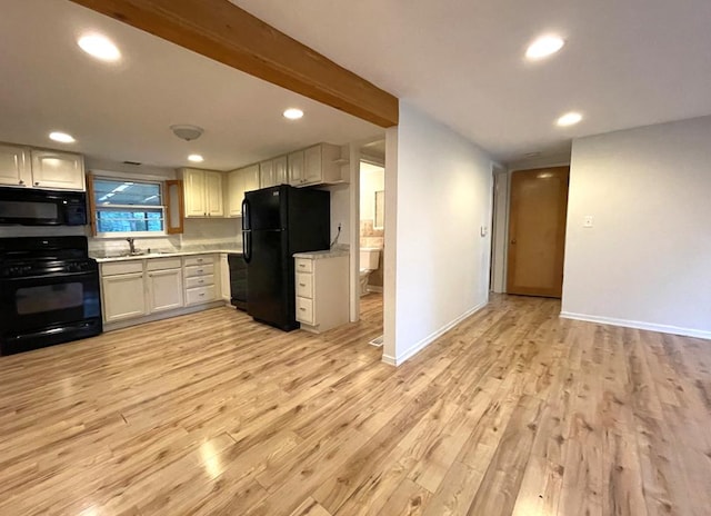 kitchen with a sink, black appliances, light countertops, and light wood-style floors