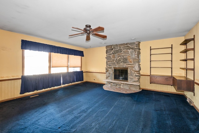 unfurnished living room featuring a fireplace, wood walls, ceiling fan, and carpet flooring