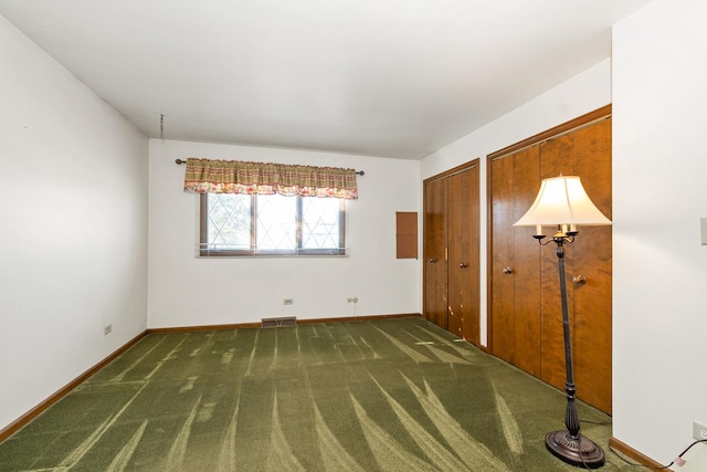 carpeted spare room featuring multiple closets