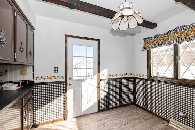 dining area with beam ceiling and light hardwood / wood-style floors