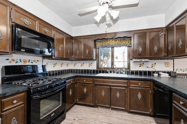 kitchen featuring dark brown cabinets, sink, backsplash, and black appliances