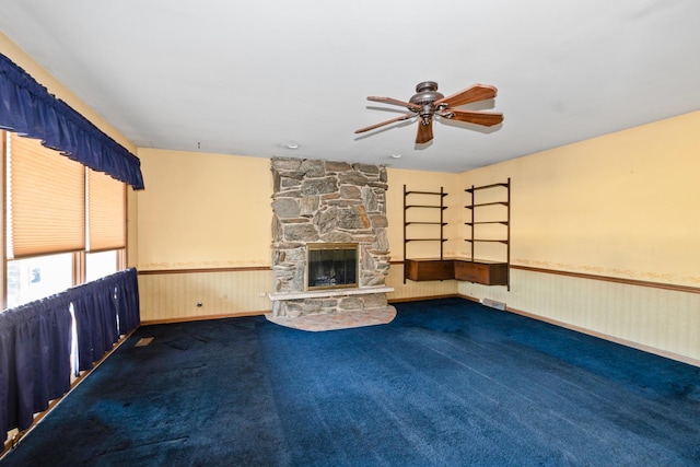 unfurnished living room with dark carpet, a fireplace, and ceiling fan