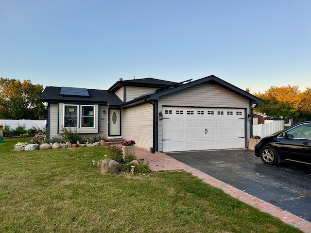 view of front of property featuring solar panels, a garage, and a front lawn