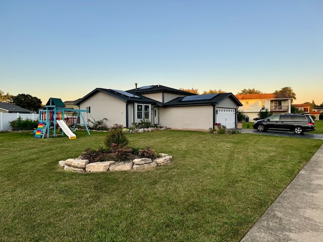 view of front of property with a garage, a playground, and a lawn