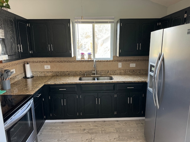 kitchen with light wood-type flooring, tasteful backsplash, stainless steel appliances, and sink