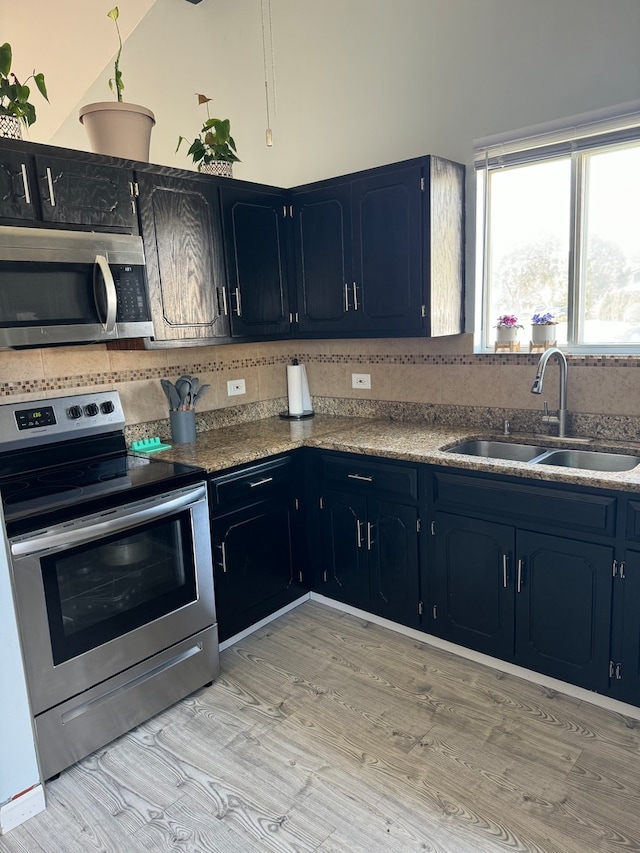 kitchen featuring appliances with stainless steel finishes, sink, light stone countertops, and light hardwood / wood-style floors