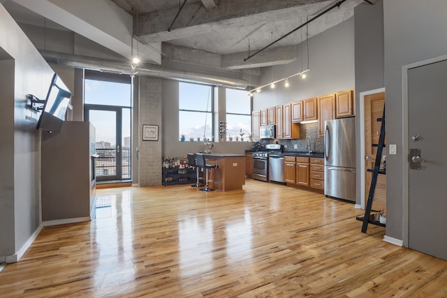 kitchen featuring a high ceiling, a kitchen breakfast bar, appliances with stainless steel finishes, and light hardwood / wood-style floors