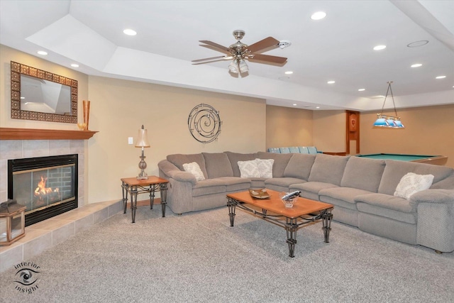 carpeted living room with a raised ceiling, ceiling fan, pool table, and a fireplace