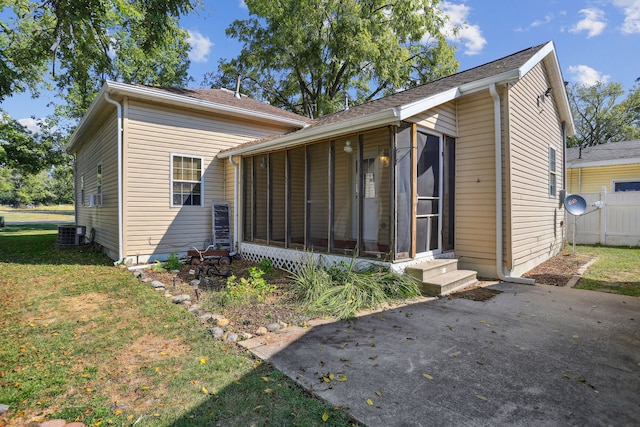 back of house with central AC unit, a sunroom, and a yard