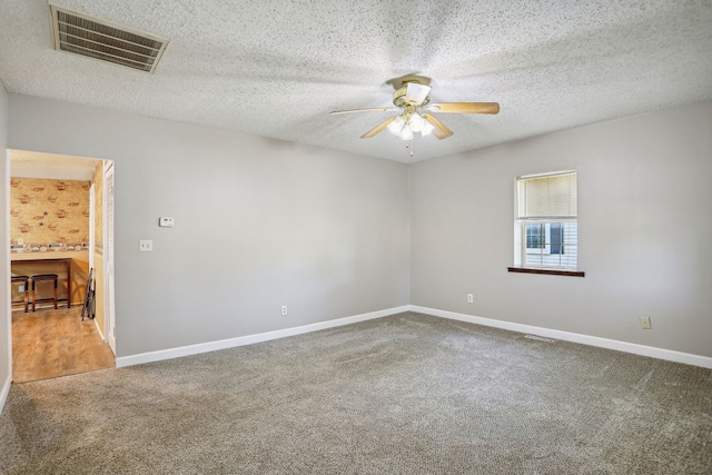 unfurnished room with ceiling fan, carpet flooring, and a textured ceiling