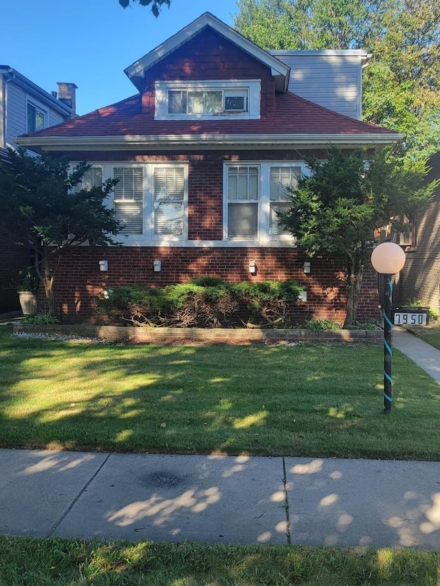 bungalow-style house with a front lawn and brick siding