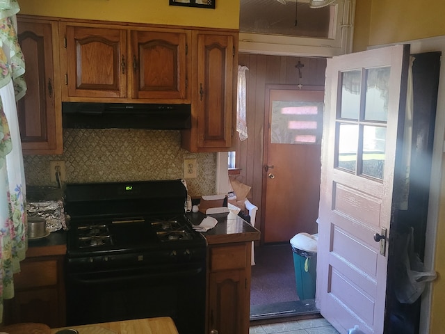 kitchen with black range with gas cooktop, light tile patterned floors, and tasteful backsplash