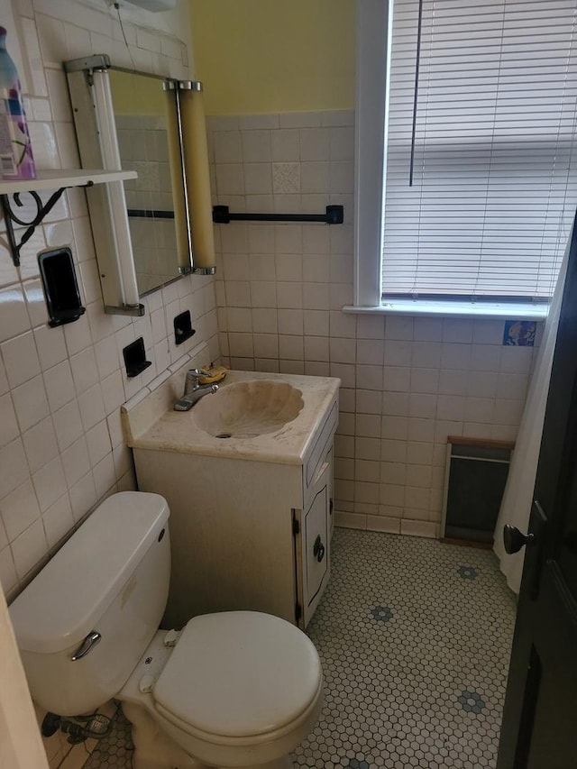 bathroom featuring vanity, toilet, tile patterned flooring, and tile walls