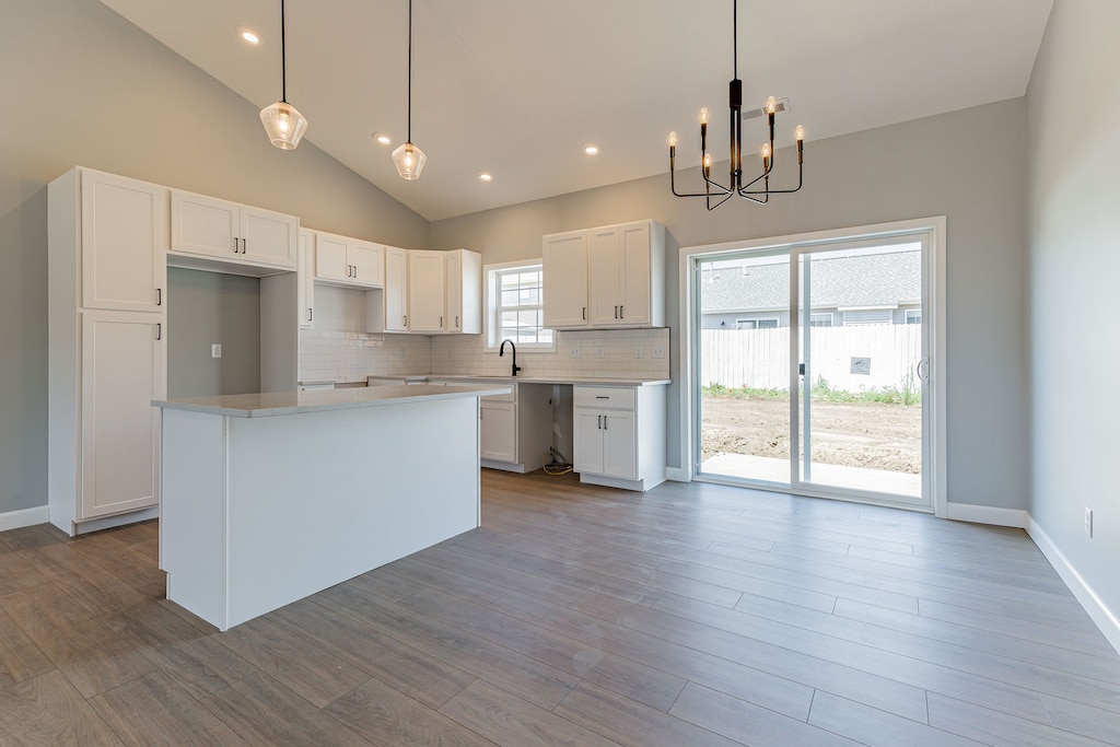 kitchen featuring decorative light fixtures, a center island, an inviting chandelier, and white cabinetry