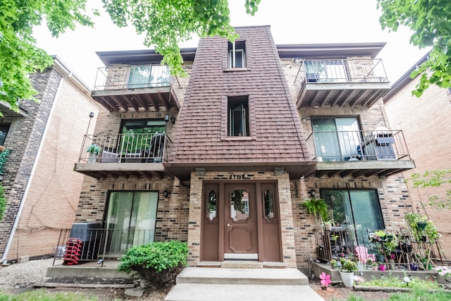 view of front of home featuring a balcony and central air condition unit