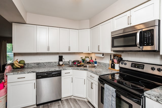 kitchen with light wood-type flooring, white cabinets, and stainless steel appliances