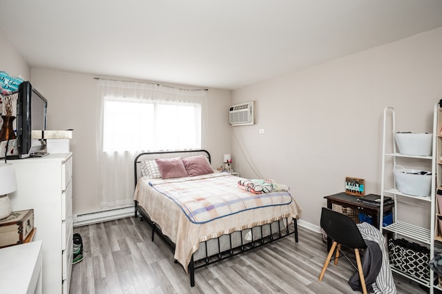 bedroom with a baseboard radiator, light hardwood / wood-style floors, and a wall mounted air conditioner