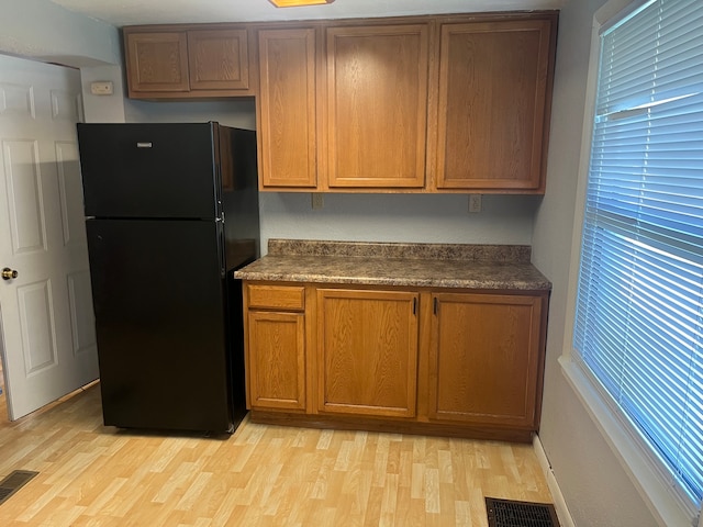 kitchen featuring black refrigerator and light hardwood / wood-style flooring