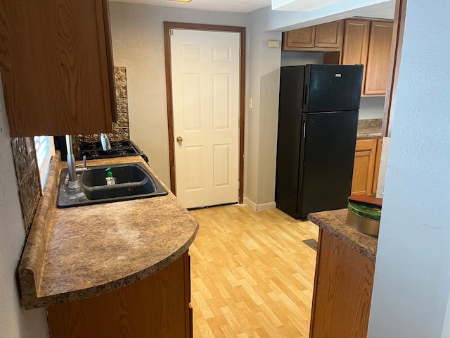 kitchen featuring black fridge, light hardwood / wood-style floors, and sink