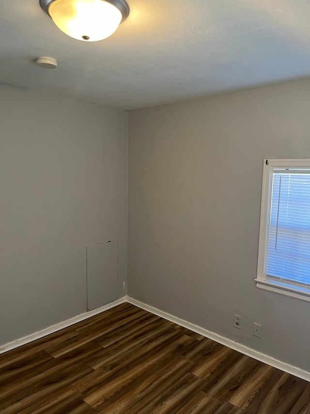 unfurnished room with dark wood-type flooring