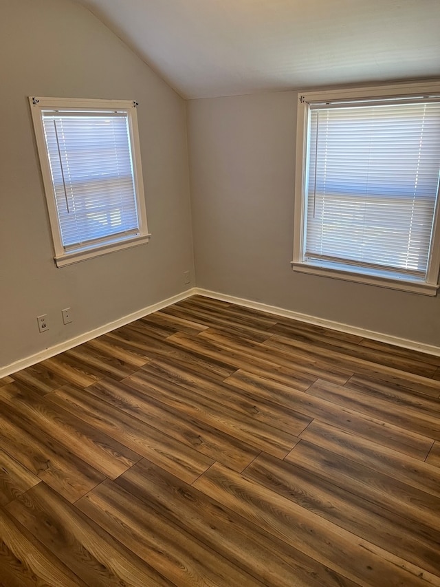 unfurnished room featuring dark wood-type flooring and lofted ceiling