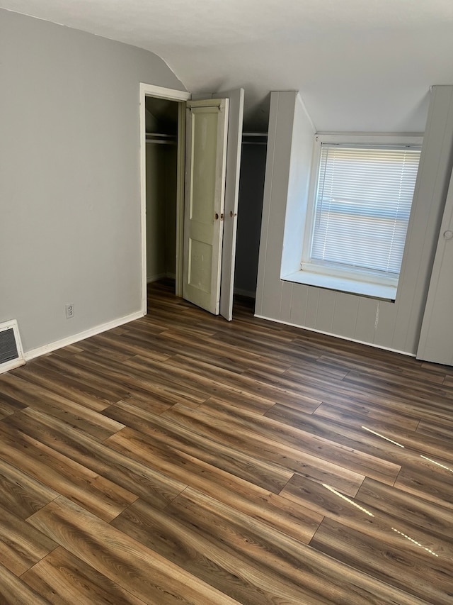 unfurnished bedroom with lofted ceiling and dark hardwood / wood-style flooring