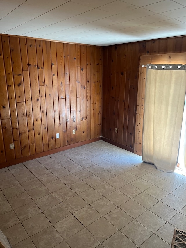 tiled spare room featuring wooden walls