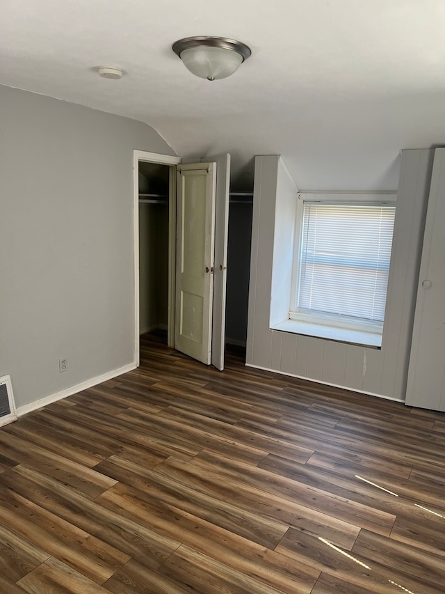 unfurnished bedroom featuring lofted ceiling and dark hardwood / wood-style flooring