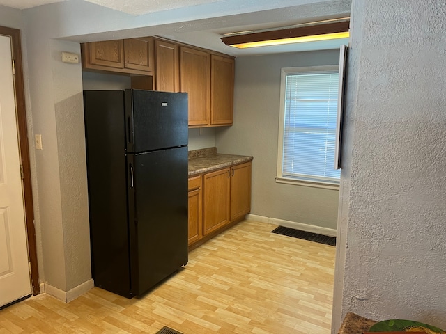 kitchen with light hardwood / wood-style flooring, black refrigerator, and a healthy amount of sunlight