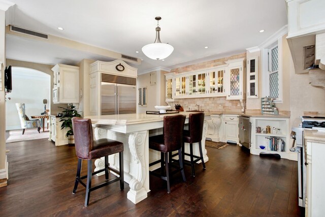 kitchen featuring decorative light fixtures, stainless steel appliances, a kitchen bar, and dark hardwood / wood-style flooring