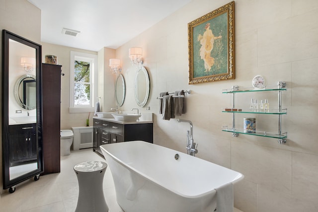 bathroom with tile patterned floors, toilet, a bathing tub, tile walls, and vanity