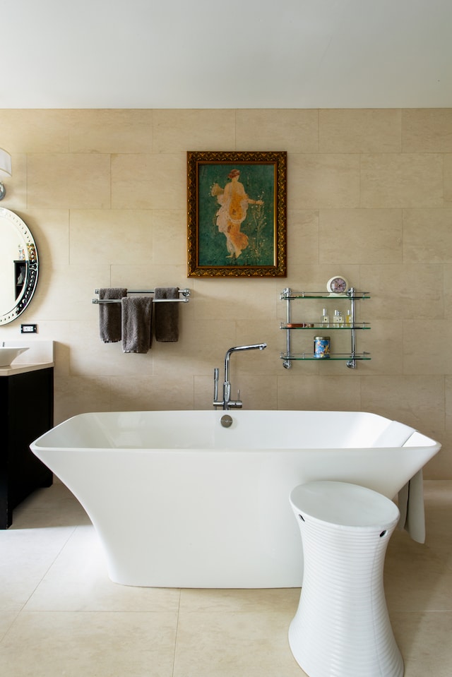 bathroom featuring vanity, a tub, tile walls, and tile patterned flooring