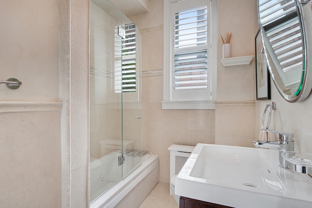 bathroom with vanity, tile walls, and shower / bath combination with glass door