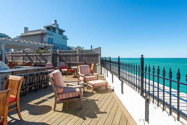 deck featuring a covered pool, exterior bar, a water view, and a pergola