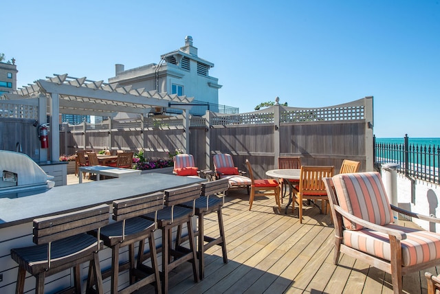 wooden terrace featuring a water view, a pergola, and a beach view