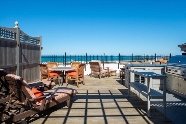 view of patio / terrace with wine cooler, a deck with water view, and a grill