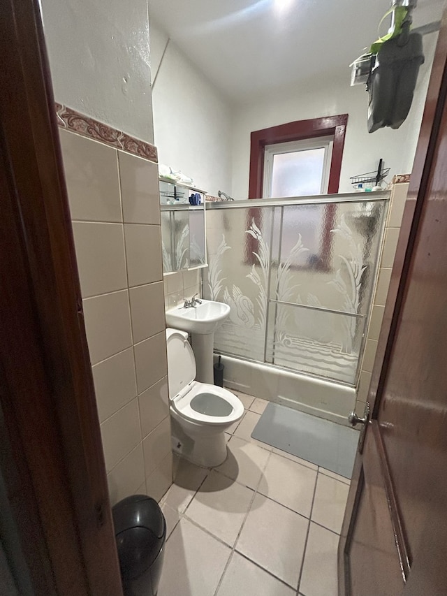 bathroom with tile patterned flooring, a shower with shower door, toilet, and tile walls