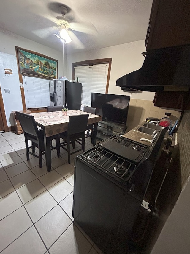 kitchen featuring black electric range oven, ceiling fan, stainless steel fridge with ice dispenser, island exhaust hood, and light tile patterned flooring