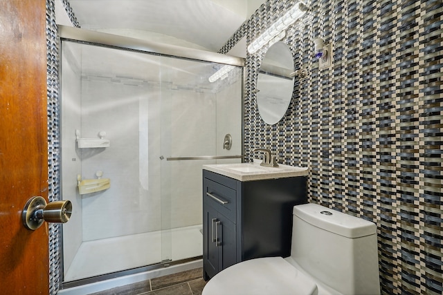 bathroom featuring vanity, toilet, tile walls, and a shower with door