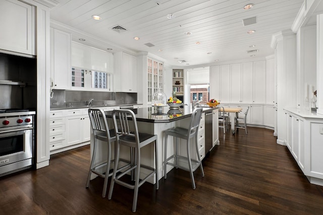 kitchen with dark wood-style flooring, white cabinetry, wooden ceiling, premium range, and a center island